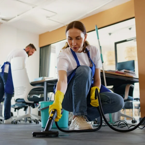 Une femme passe l'aspirateur dans une pièce, nettoyant le sol avec soin.