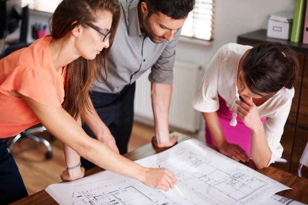 Équipe analysant les plans d’un projet de rénovation pour anticiper les défis du chantier